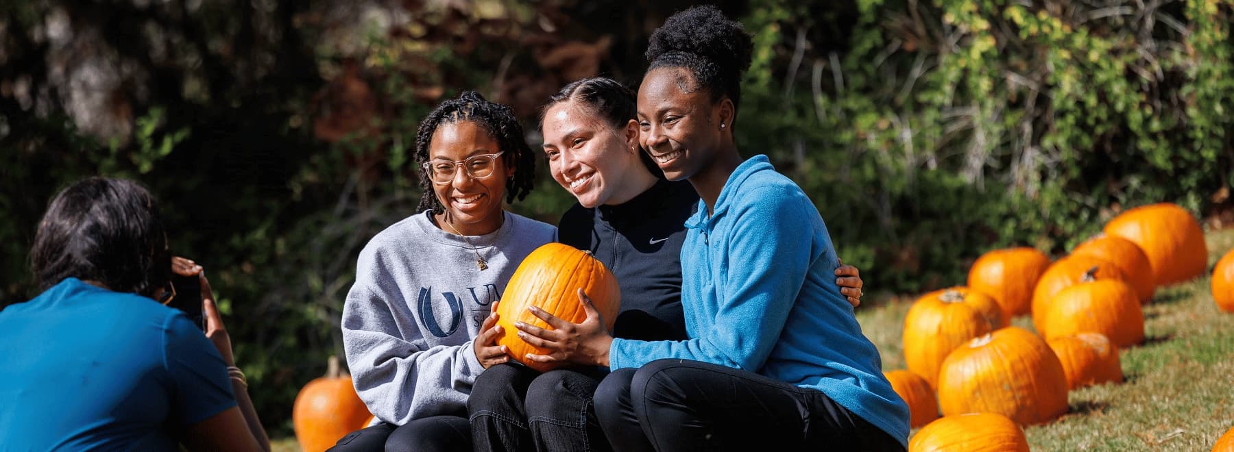 Three female students pose for a photo with a pumpkin